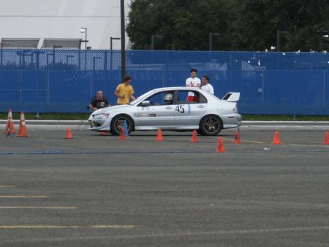 2001 Mercury Grand Marquis - Silver Mitsubishi Lancer Evolution with racing decals and number 45 on door, parked on asphalt with orange cones.