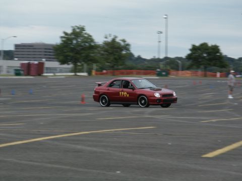 2001 Mercury Grand Marquis - A red sedan navigates a course marked by cones on a cloudy day.