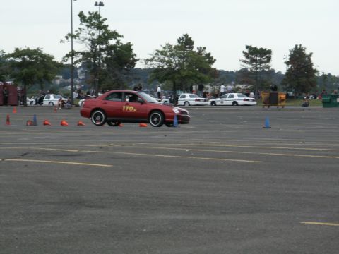 2001 Mercury Grand Marquis - A red sedan, marked with the number 170, participates in a timed driving event on a paved course.