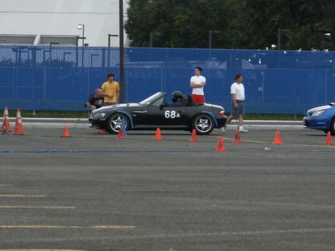 2001 Mercury Grand Marquis - A black convertible sports car with racing number 68A is on a track with orange cones, a blue car is also visible.