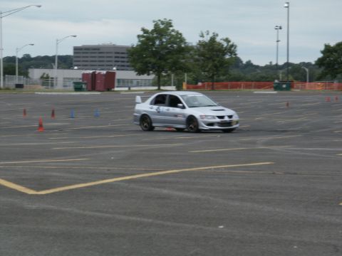 2001 Mercury Grand Marquis - A silver sedan with a prominent rear spoiler is seen on a paved lot marked with cones.
