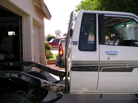1986 Toyota Hilux - Side view of a 1986 Toyota Hilux, with its chassis in the foreground and another vehicle in the background.