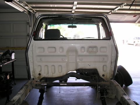 1986 Toyota Hilux - The rear of a pickup truck cab and chassis is shown, with the bed removed, inside a garage.