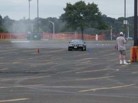 2001 Mercury Grand Marquis - A black convertible sports car drifts in a parking lot, leaving a trail of smoke.