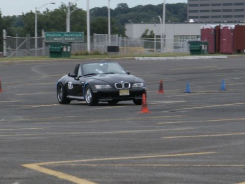 2001 Mercury Grand Marquis - A black convertible sports car, possibly a BMW Z3, is seen on a race track with orange and blue cones marking the course.