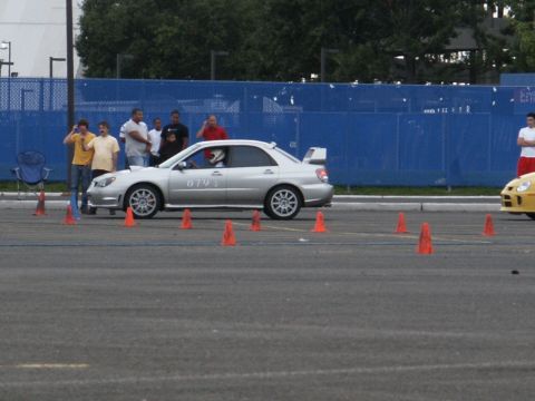 2001 Mercury Grand Marquis - A silver sedan navigates a cone course, with spectators watching in the background.