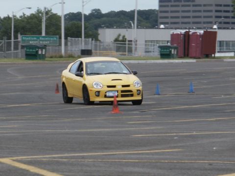 2001 Mercury Grand Marquis - A yellow Dodge Neon SRT-4 is shown on a paved lot with orange and blue cones, likely during a driving event.