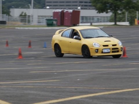 2001 Mercury Grand Marquis - A yellow Dodge Neon SRT-4 sedan is seen during a timed driving event on a paved lot.