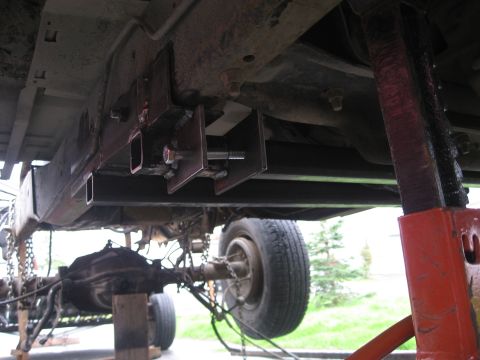 1990 Ford F-250 - Custom metal fabrication is being installed on the undercarriage of a truck.