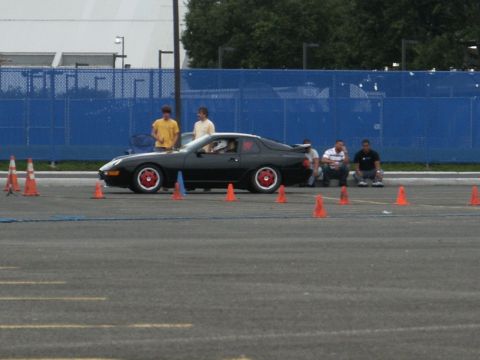 2001 Mercury Grand Marquis - A black sports coupe is positioned on a paved lot, surrounded by traffic cones, with spectators observing.
