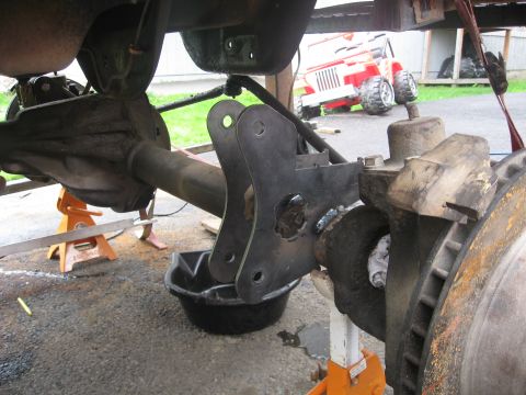 1990 Ford F-250 - Custom bracket welded onto a rear axle assembly, with a red Jeep visible in the background.