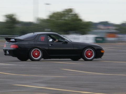 2001 Mercury Grand Marquis - A black coupe with distinctive red wheels is captured in motion on a paved surface, possibly a track or parking lot.