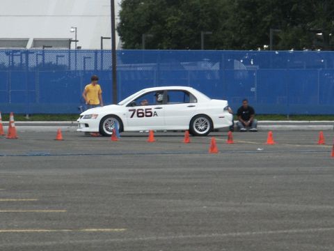 2001 Mercury Grand Marquis - A white sedan with racing numbers is set up on a course marked by orange cones, with two people observing.