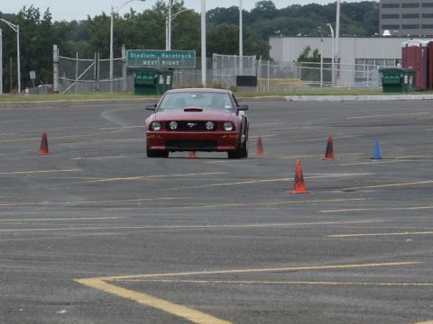 2001 Mercury Grand Marquis - A red Ford Mustang navigates a cone course in a parking lot.