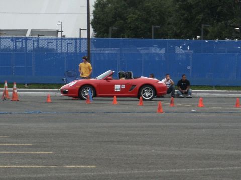 2001 Mercury Grand Marquis - A red convertible sports car is staged on a course marked by orange cones, with spectators watching.