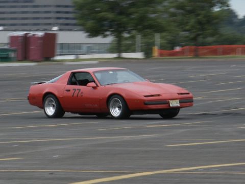 2001 Mercury Grand Marquis - This red Pontiac Firebird, marked with '77c', is captured in motion on a paved surface.