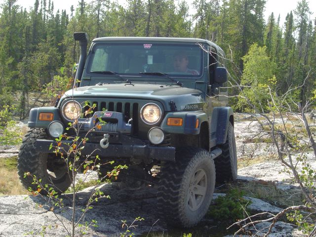 Green Jeep Wrangler Rubicon with winch on rocky terrain