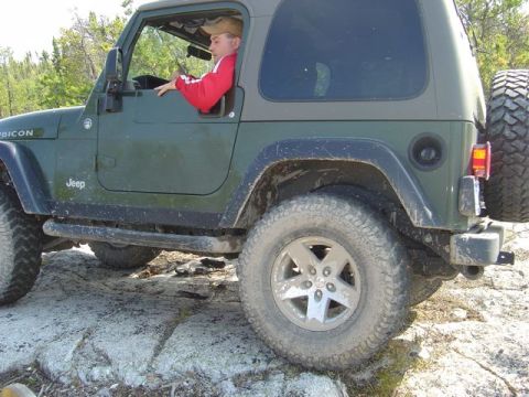 1986 Ford F-150 - A green Jeep Wrangler Rubicon navigates a rocky off-road path.