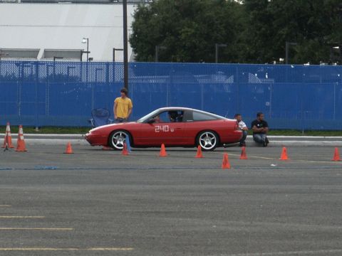 2001 Mercury Grand Marquis - A red sports coupe is positioned on a track with orange cones, suggesting a timed event.