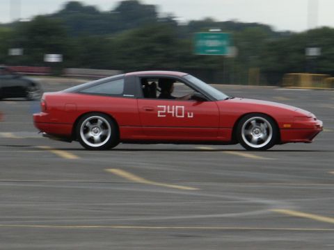 2001 Mercury Grand Marquis - A red sports coupe with "240" displayed on its side is captured in motion on a paved surface.
