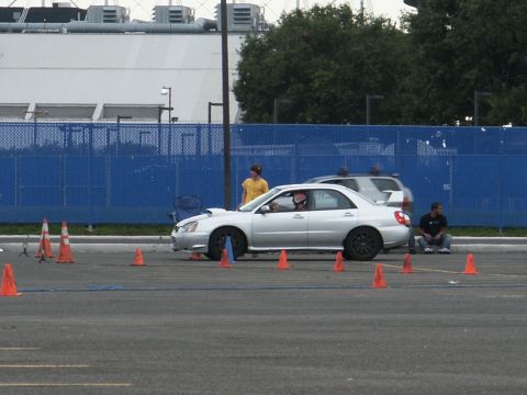 2001 Mercury Grand Marquis - A silver sedan participates in an autocross event, with cones marking the course and spectators observing.