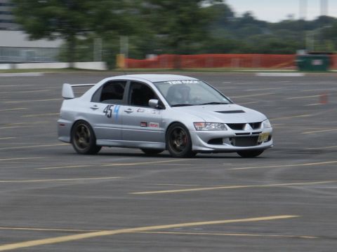 2001 Mercury Grand Marquis - A silver Mitsubishi Lancer Evolution sedan navigates a course, displaying racing decals and the number 454.