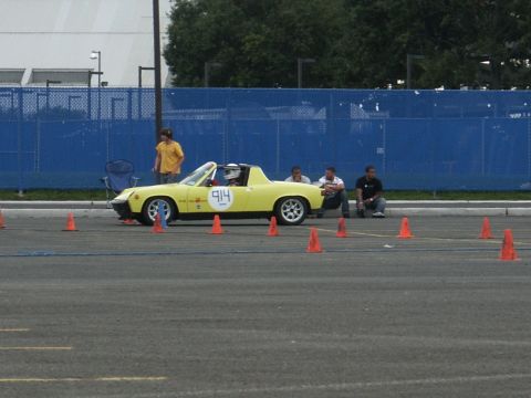 2001 Mercury Grand Marquis - A yellow sports car, marked with the number 914, is positioned on an asphalt lot surrounded by orange cones, suggesting a timed event.