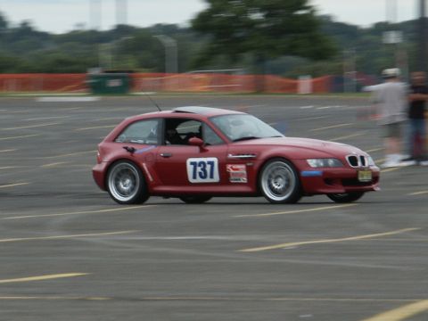 2001 Mercury Grand Marquis - Red BMW M coupe with racing number 737 on side, driving on asphalt track during an event.