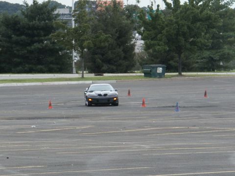 2001 Mercury Grand Marquis - A black Pontiac Firebird navigates a cone course in an empty parking lot.