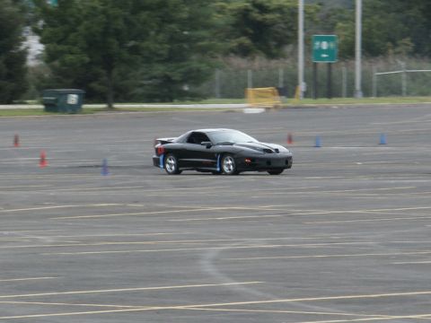 2001 Mercury Grand Marquis - A black 2001 Pontiac Firebird navigates a course marked by cones on a paved lot.