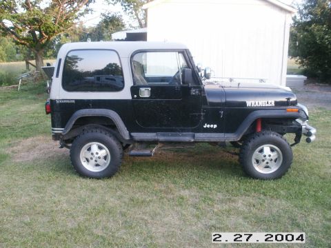1992 Ford Mustang - This Jeep Wrangler has a two-tone black and grey exterior and is parked outdoors on a grassy lawn.