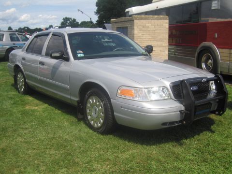 1991 Ford LTD Crown Victoria - silver Ford Crown Victoria police sedan with a front push bar bearing the Ford oval, parked on grass at an outdoor display.