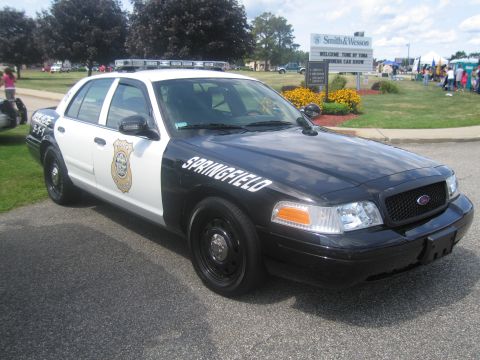 1991 Ford LTD Crown Victoria - black-and-white Ford Crown Victoria police interceptor lettered "Springfield" parked on pavement at an outdoor car show.