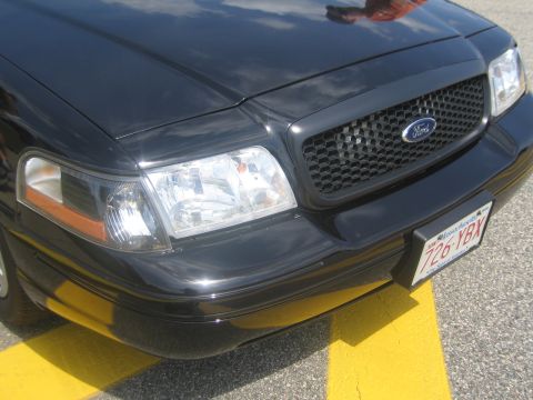 1991 Ford LTD Crown Victoria - Close-up of the front grille, Ford emblem, headlight and Massachusetts plate 726-YBX on a black sedan.
