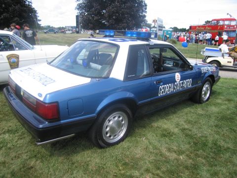 1991 Ford LTD Crown Victoria - Rear three-quarter view of a blue-and-white Ford Mustang marked "Georgia State Patrol" with light bar, on grass.