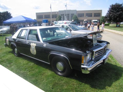 1991 Ford LTD Crown Victoria - black-and-white full-size Ford police sedan numbered 45 with hood open and police shield on the door, on grass.