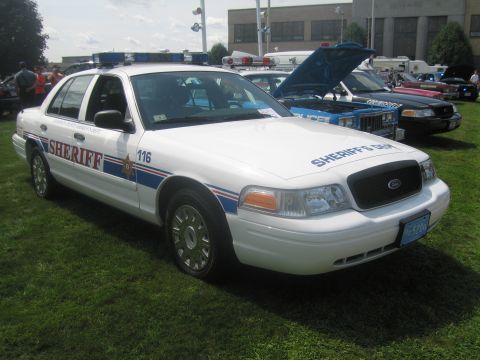 1991 Ford LTD Crown Victoria - white Ford Crown Victoria sheriff's cruiser lettered "Sheriff" and numbered 116 with roof light bar, parked on grass.