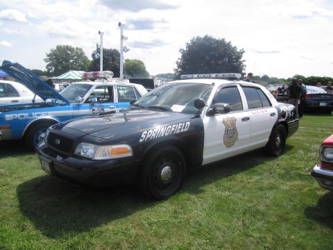 1991 Ford LTD Crown Victoria - black-and-white Ford Crown Victoria police cruiser lettered "Springfield" with roof light bar, parked on grass.