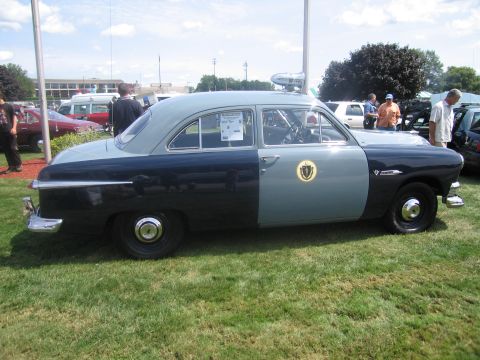 1991 Ford LTD Crown Victoria - Passenger-side profile of a restored two-tone blue vintage Ford two-door police coupe with roof light and agency seal, parked on grass.