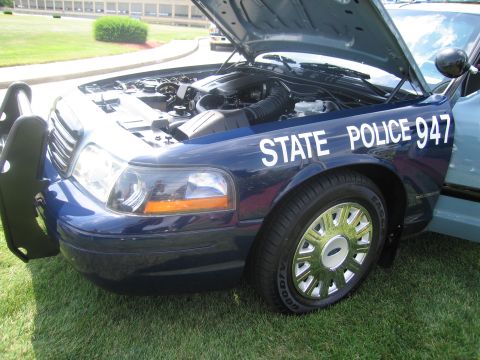 1991 Ford LTD Crown Victoria - Front three-quarter view of a dark blue Ford State Police car with hood raised, lettered STATE POLICE 947 on the front door.