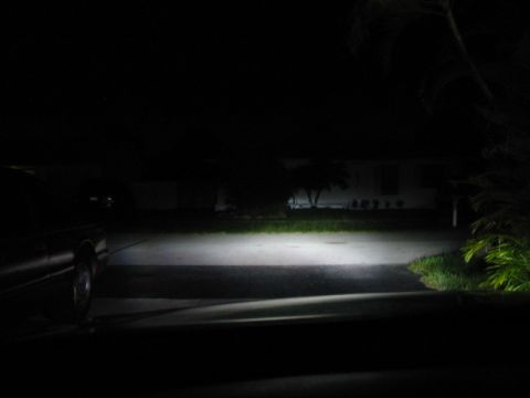 1995 Ford Thunderbird - The bright headlights of a car cut through the darkness of a residential driveway at night.