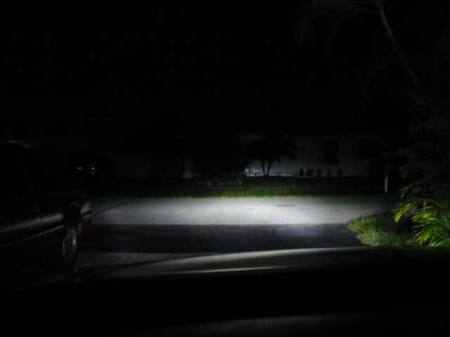 Car's headlights illuminate a dark driveway at night