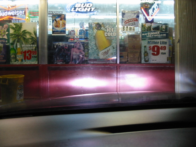 Car headlights illuminating a store window display with beer advertisements