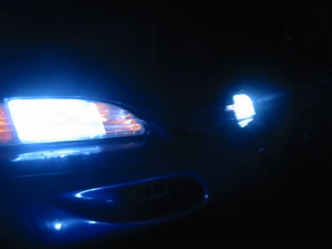 1995 Ford Thunderbird - The bright blue headlights of a car illuminate the dark night.