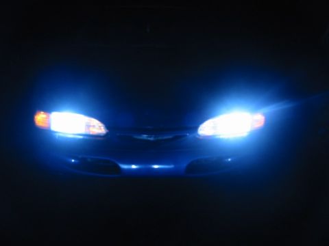 1995 Ford Thunderbird - The front of a blue 1995 Ford Thunderbird is visible at night, illuminated by its bright headlights.