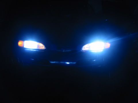 1995 Ford Thunderbird - The bright headlights of a car are illuminated against the dark night sky.
