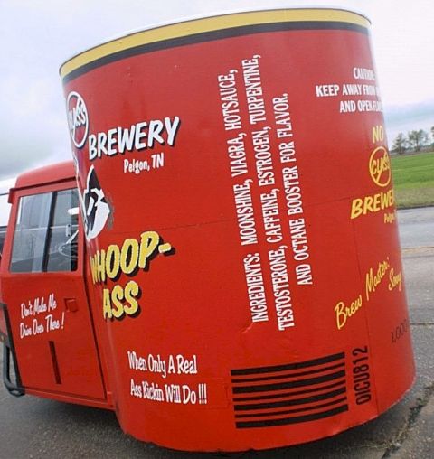 1987 Ford Thunderbird - A truck is modified to carry a large cylindrical advertisement for 'Whoop-Ass' brewery.