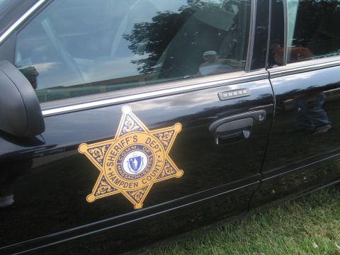 1991 Ford LTD Crown Victoria - Close-up of a gold six-point Sheriff's Dept Hampden County Massachusetts star decal on the black door of a patrol car.