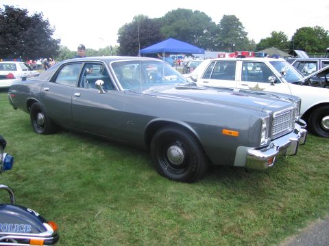 1991 Ford LTD Crown Victoria - two-tone gray 1970s full-size four-door sedan with black steel wheels, parked on grass among other vehicles at a show.