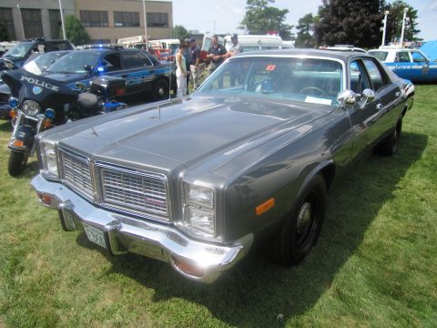 1991 Ford LTD Crown Victoria - Front-three-quarter view of a gray 1970s full-size sedan with quad stacked headlights and chrome grille, parked on grass at a show.